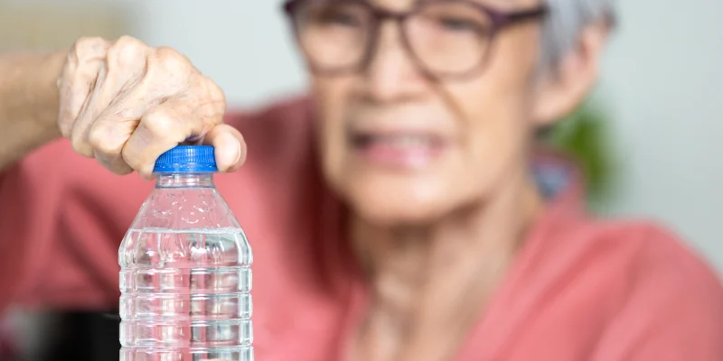 Trouble opening the bottle of drinking water in the elderly age,life problem,senior woman with numbness and weakness of hands and fingers muscle,difficulty in turning or unscrewing cap of water bottle