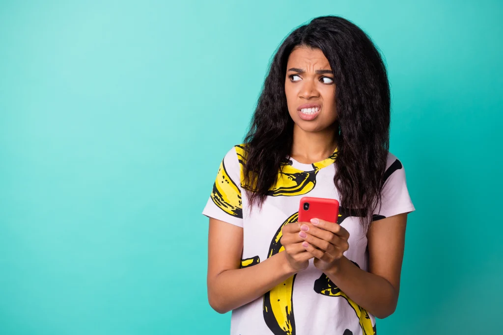 Photo of disgusted displeased girl hold phone look empty space wear banana print t-shirt isolated turquoise color background
