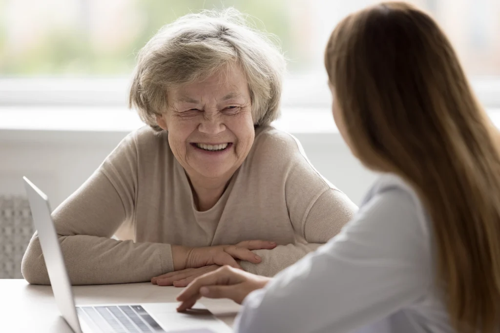 older lady talking to a younder lady with a laptop nearby