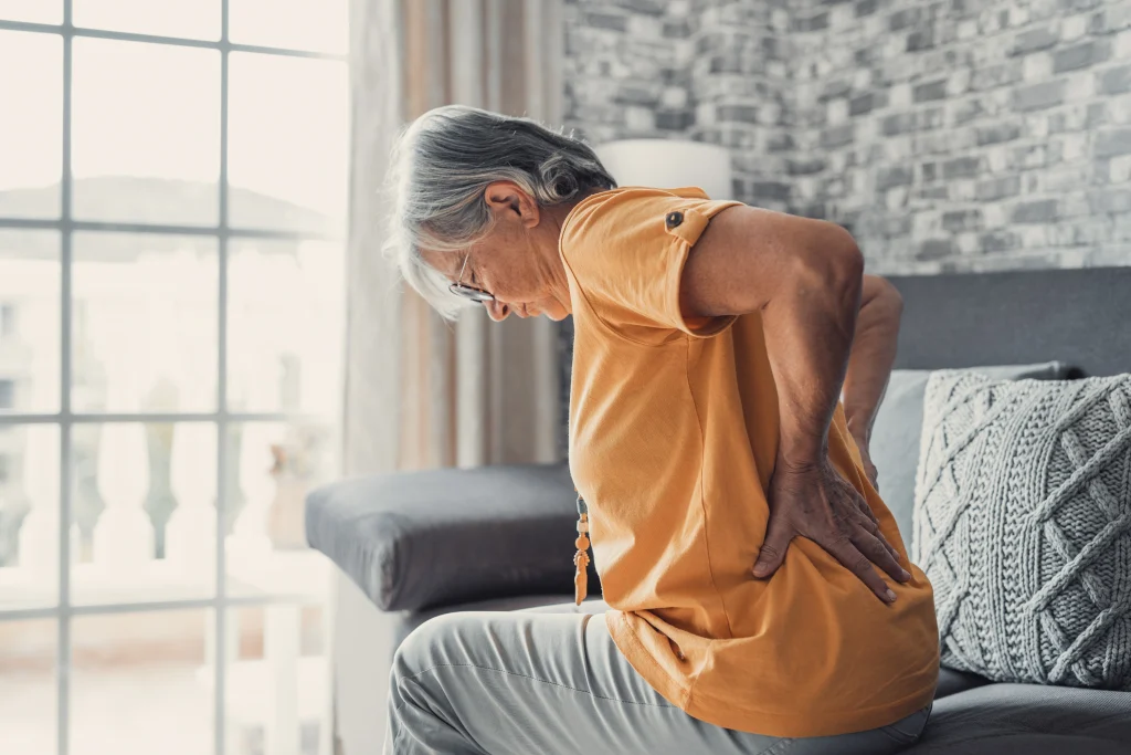 senior woman sitting on couch with osteoporosis back pain