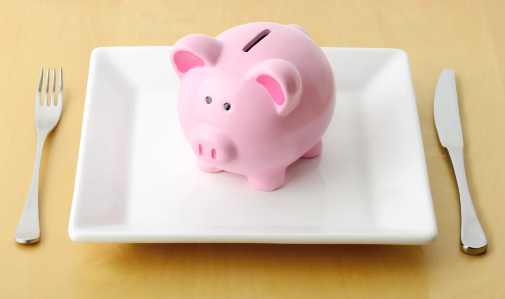 Piggy bank on the plate with fork and knife