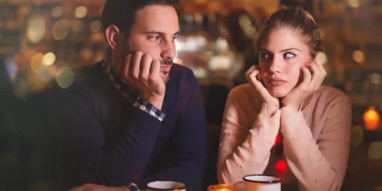 annoyed couple sitting looking bored at a restaurant or meal with family on a holiday like thanksgiving or christmas