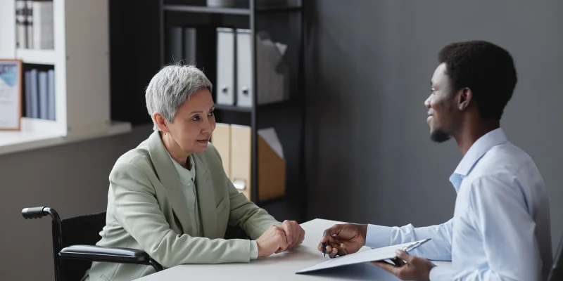 Side view portrait of mature woman with disability speaking to recruiter in job interview