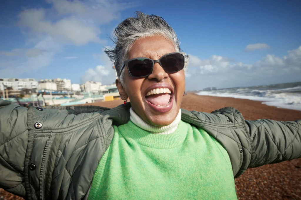 senior flinging arms outside at the beach