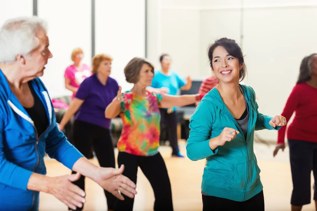 a group of seniors taking line dancing lessons from a young brunette instructor