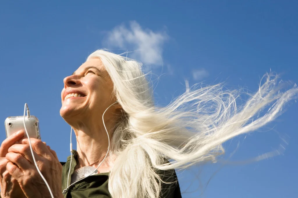 older lady hair flying smiling against the sky