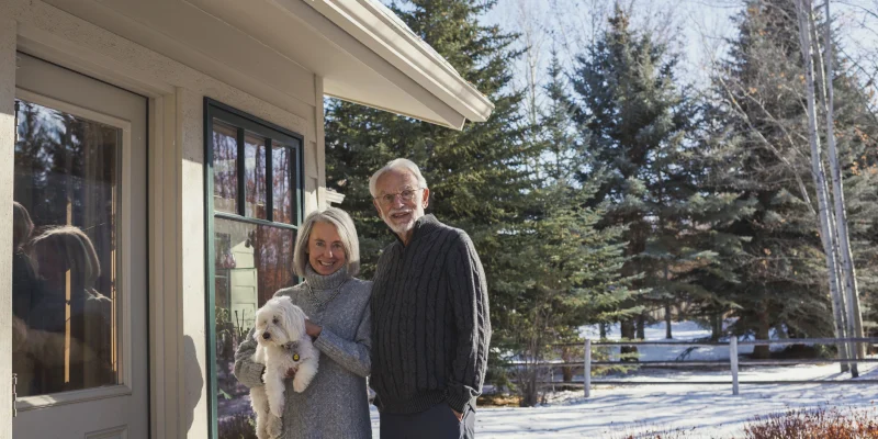 senior couple outside of their home smiling in the snow