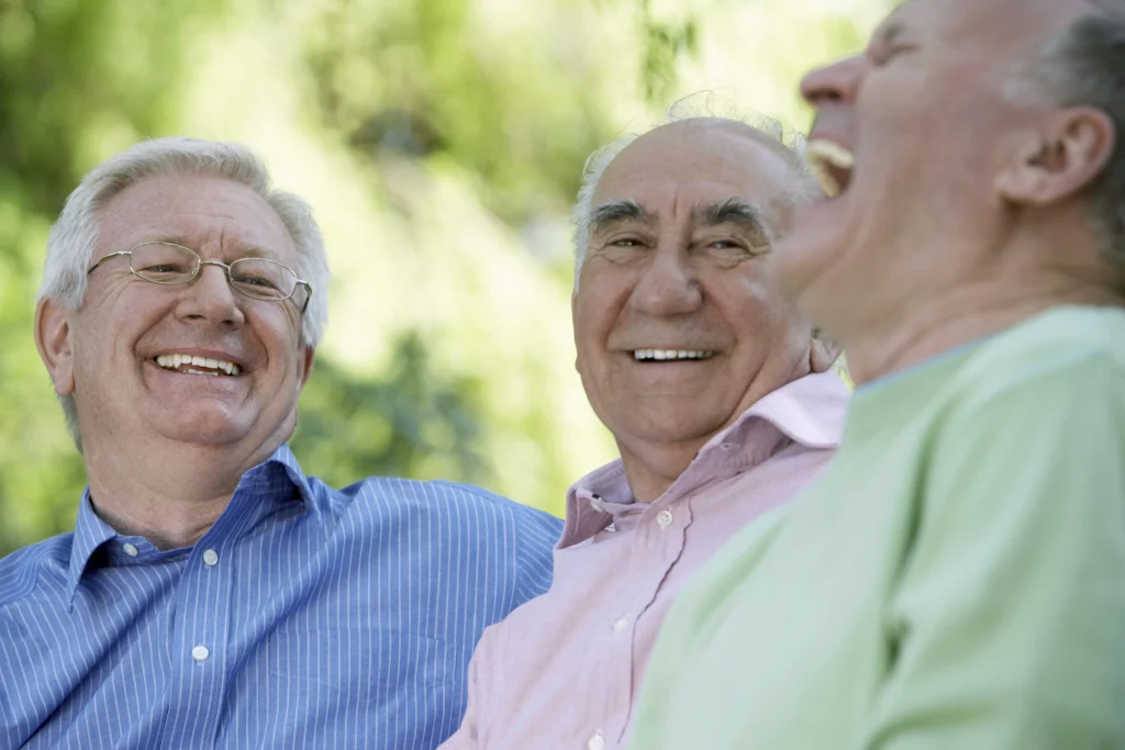 Three senior men laughing, close-up (focus on man wearing glasses) - stock photo