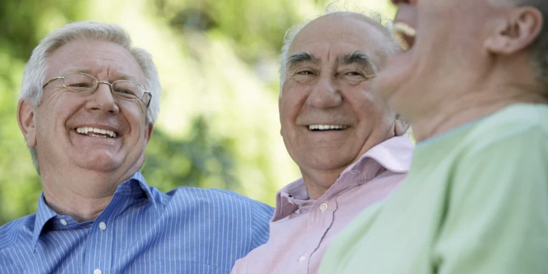 Three senior men laughing, close-up (focus on man wearing glasses) - stock photo