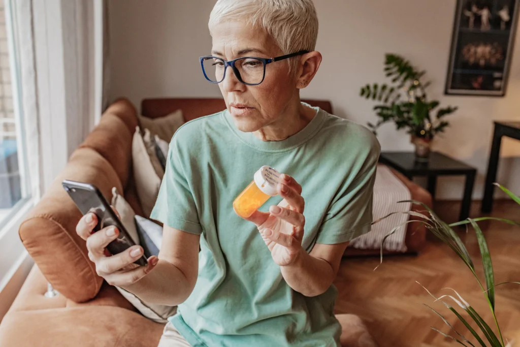 senior woman with glasses searching a 2025 Medicare prescription plan on her phone