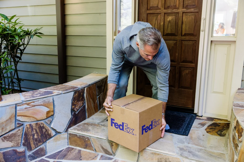 senior man grabbing a fedex box off his front porch