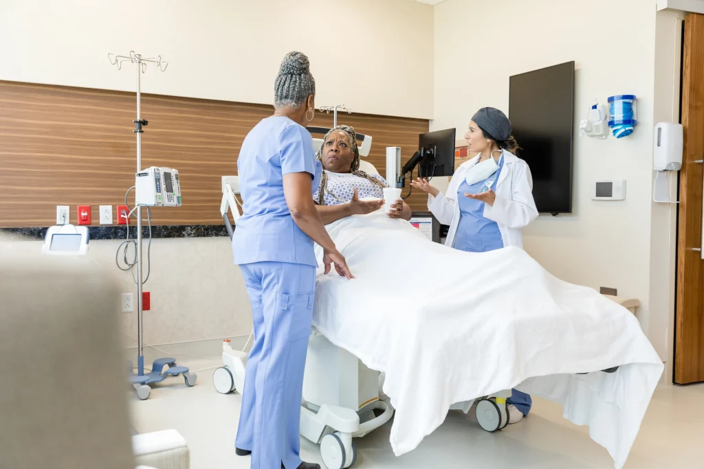 black woman in hospital bed arguing with two doctors who aren't listening to her concerns