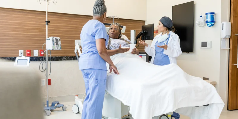 black woman in hospital bed arguing with two doctors who aren't listening to her concerns