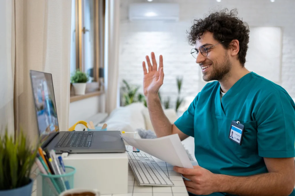 man in scrubs waving at camera