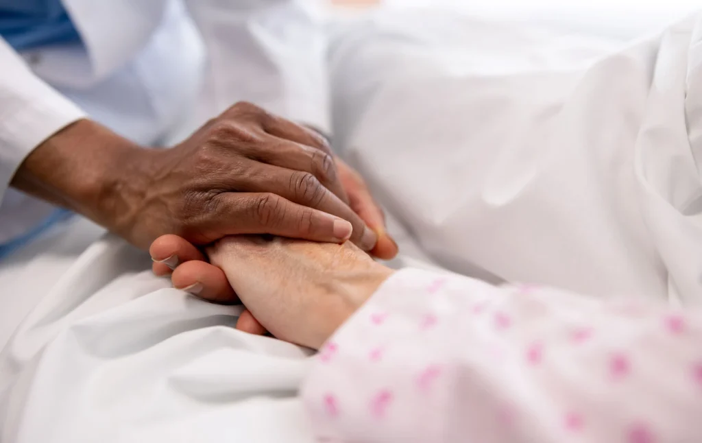hand clasping patient's hand hospice