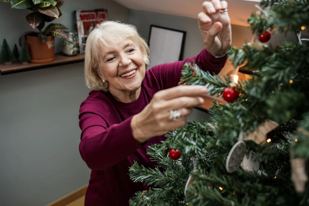 older lady hanging up christmas ornaments