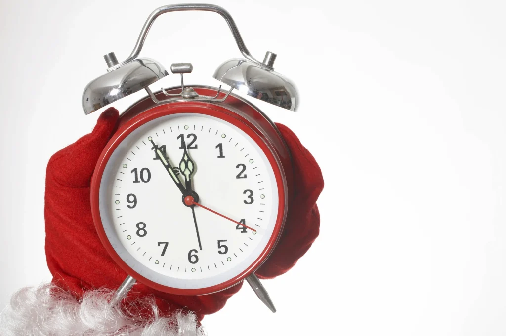last minute holiday gift concept with an alarm clock being held by santa