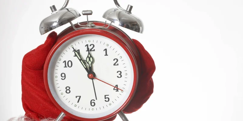 last minute holiday gift concept with an alarm clock being held by santa