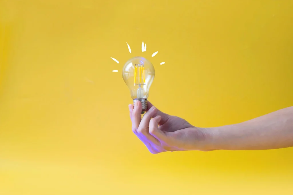 yellow background hand holding a lightbulb