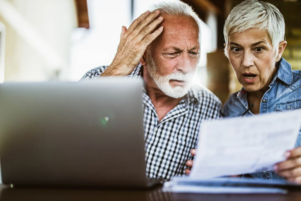 omg senior couple looking stunned at a bill and their computer screen