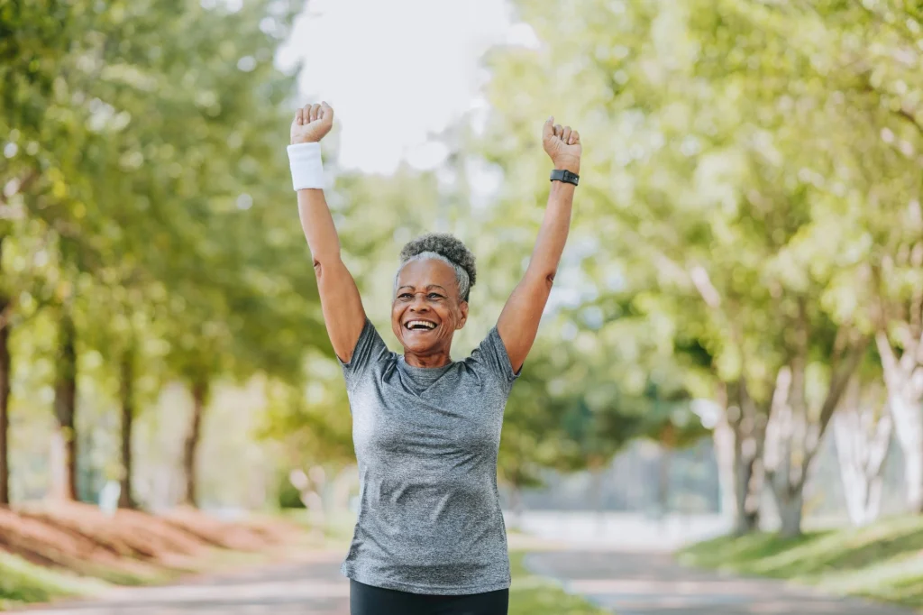 senior lady running outside with arms raised