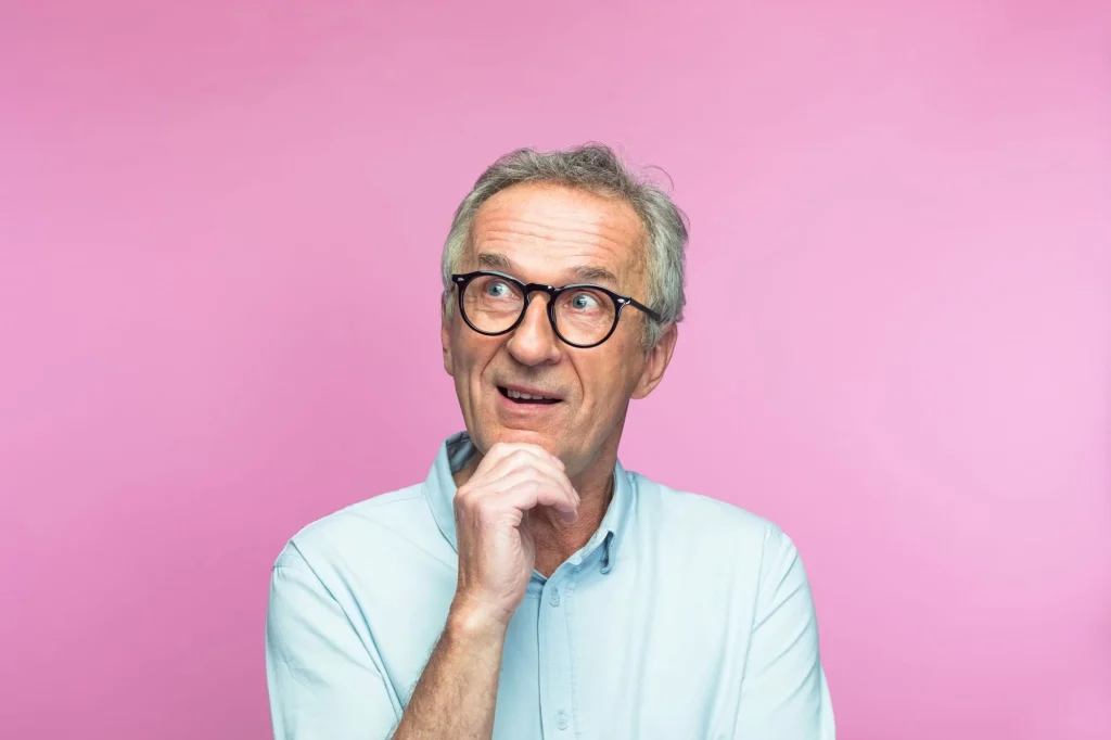 senior man thinking with a pink background