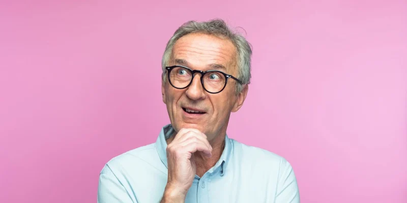 senior man thinking with a pink background