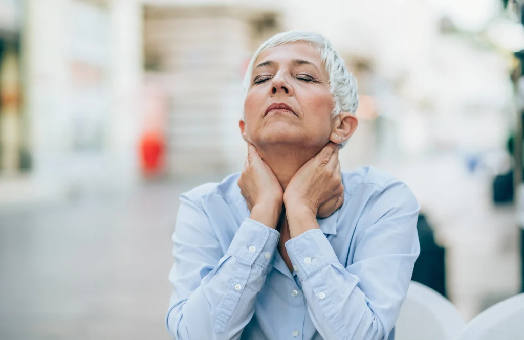 senior adult woman with gray short hair standing in a street feeling stressed and trying to relax with eyes closed