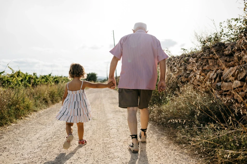 granddad and granddaughter walking down dirt road hand in hand