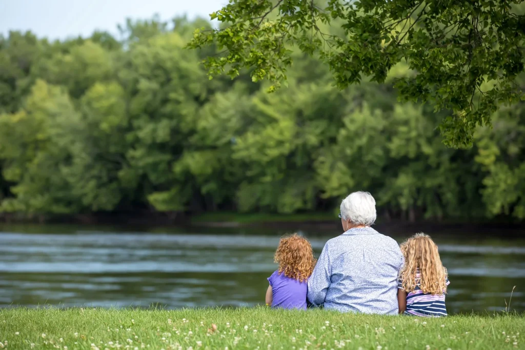 grandma and granddaughters sitting beside the lake