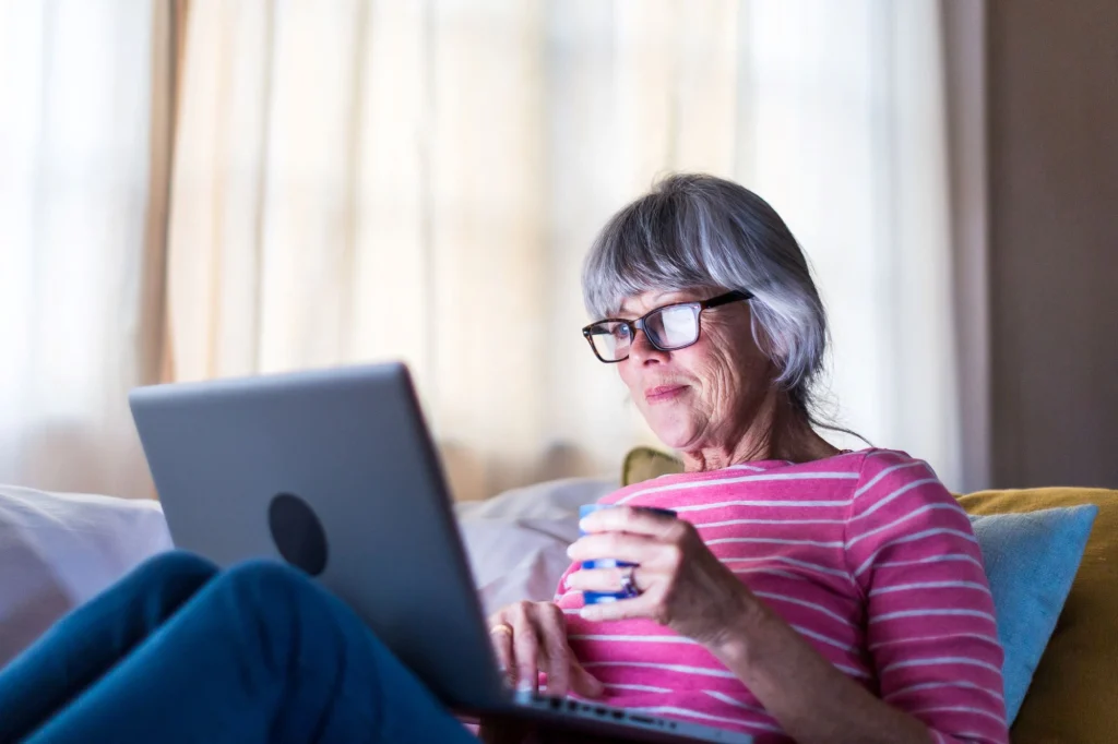 older lady on a laptop with a cup of coffee