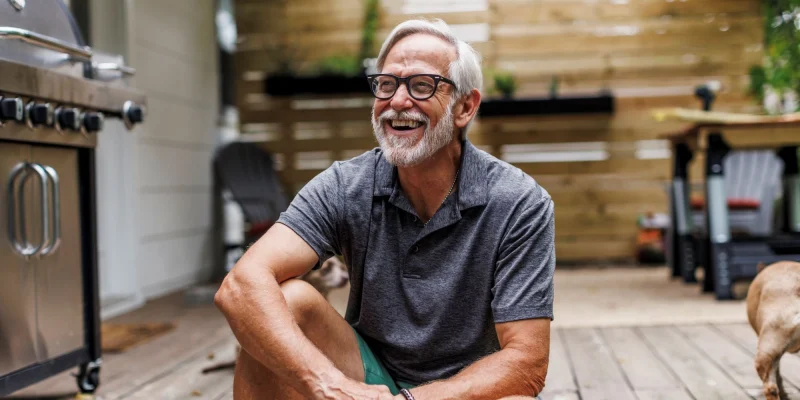 retired man with white hair and beard sitting outside smiling