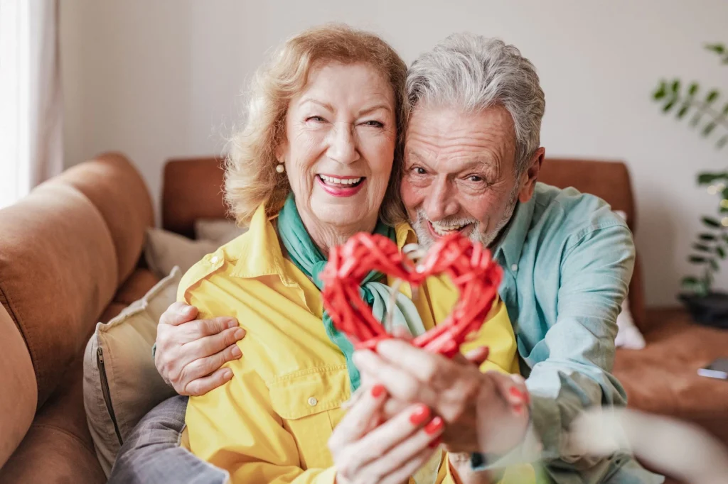 senior couple on couch holding a heart valentine's day