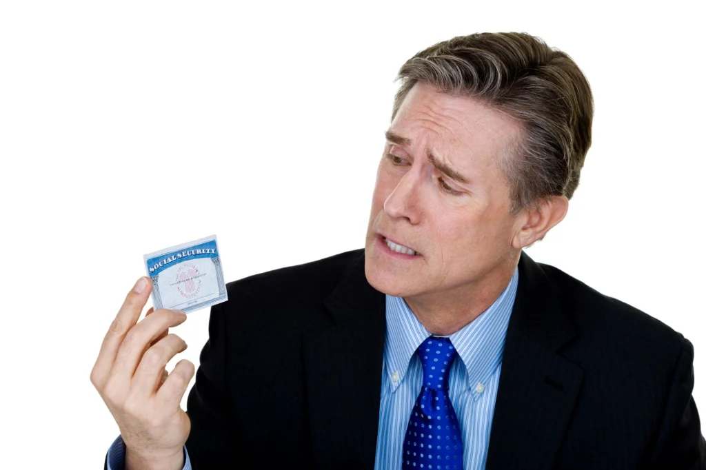 Man holding a social security card looking confused and distraught. 