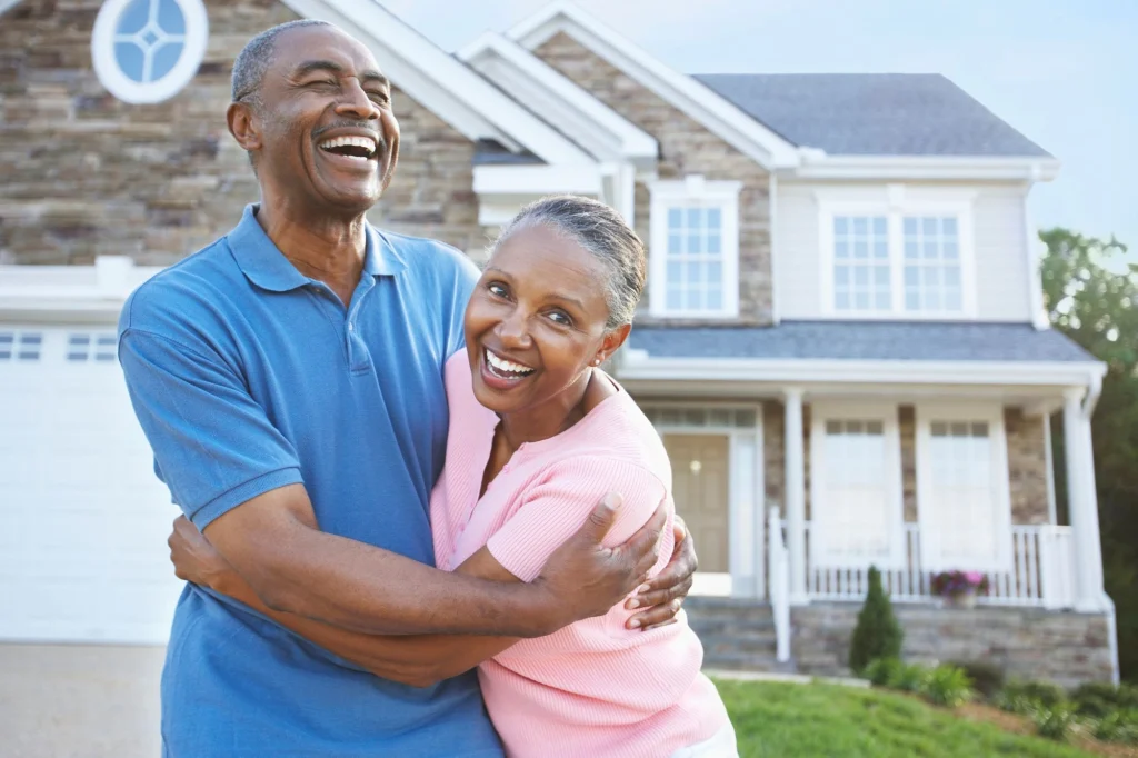 senior couple hugging in front of their house