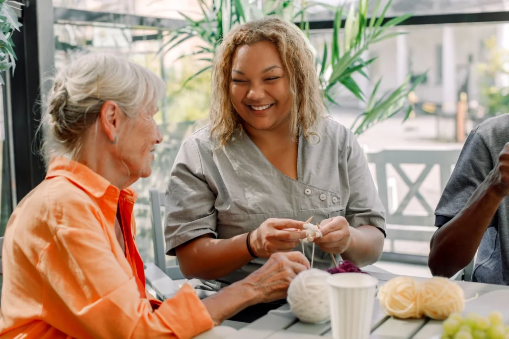 lady in orange shirt knitting with her nurse
