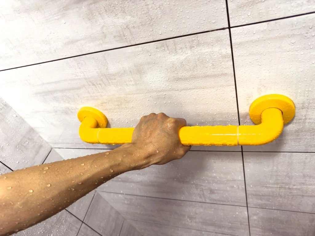 hand gripping yellow grab bar in the shower