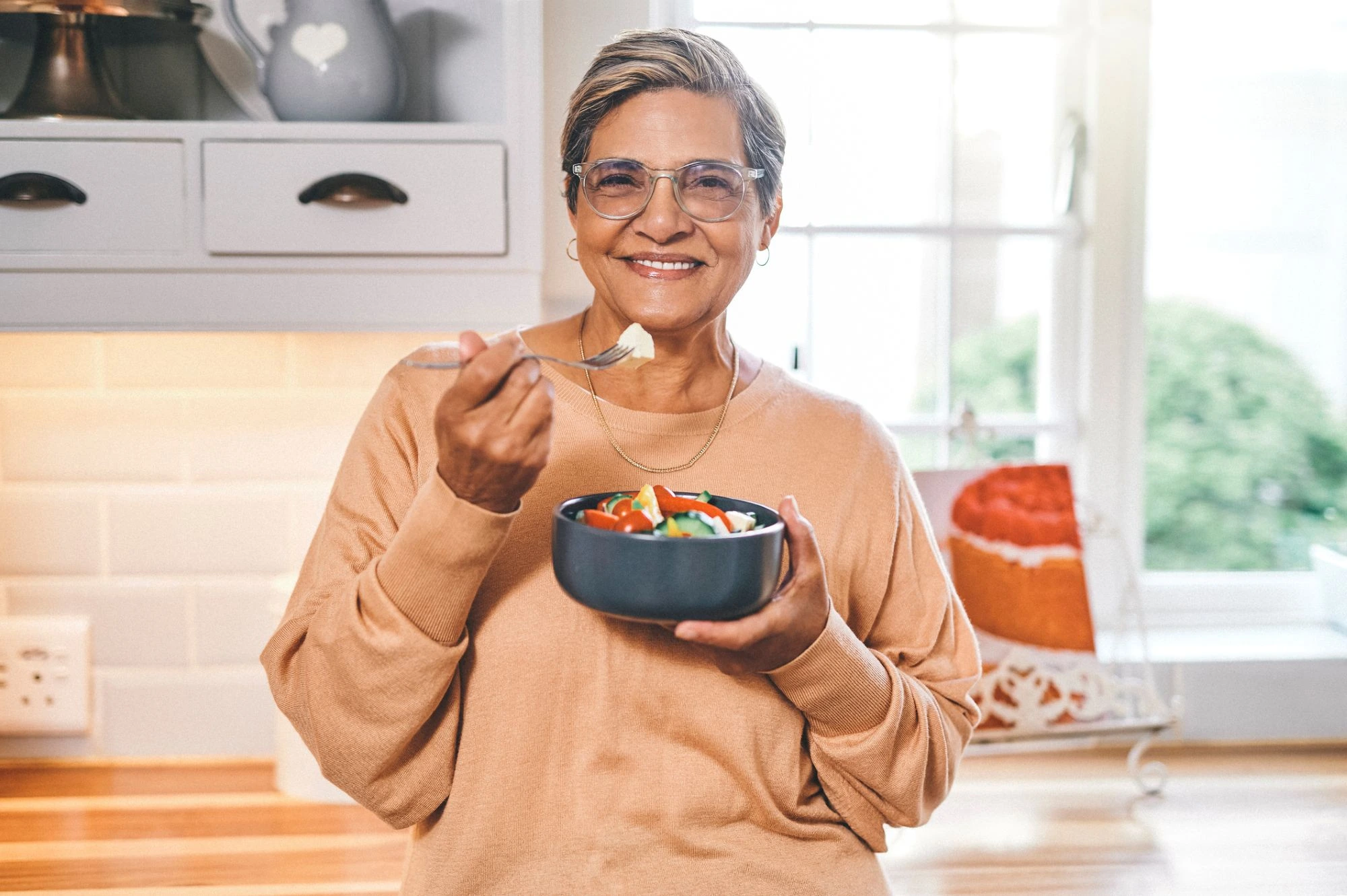 happy lady eating a healthy meal in her kitchen